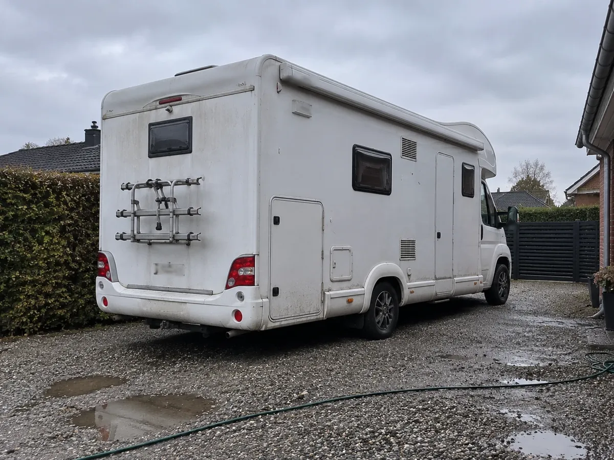 Autocamper parkeret i en grusindkørsel ved et parcelhus
